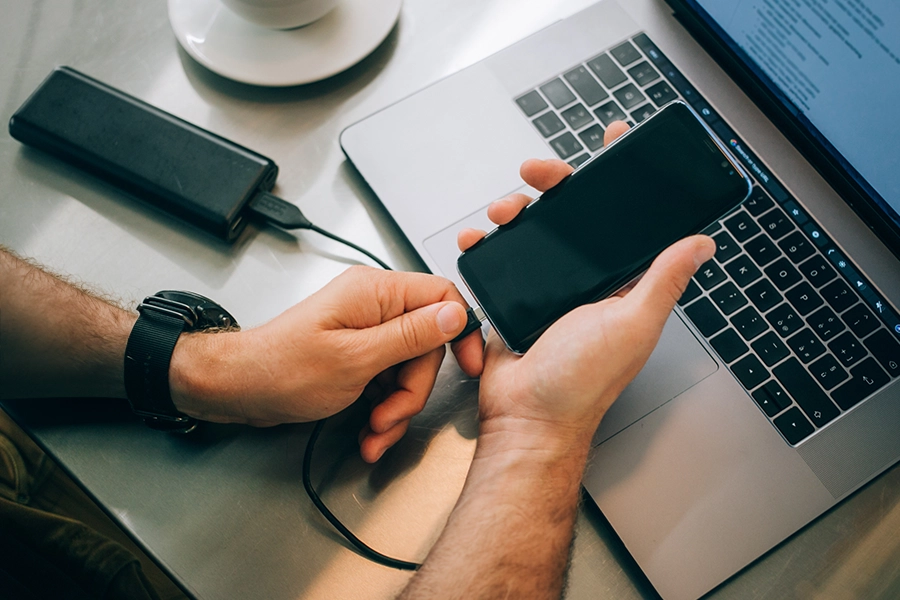 Over the shoulder shot of a man using a USB-C cord on his smart phone in Springfield, IL.