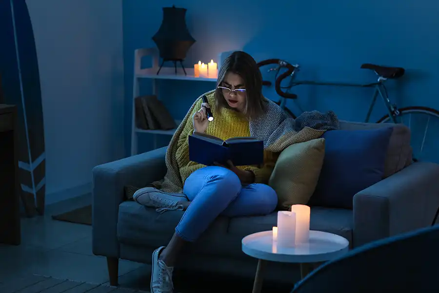 Ruby Electric, Inc.—A young woman using candles and a flashlight during a power outage in her home in Springfield, IL.