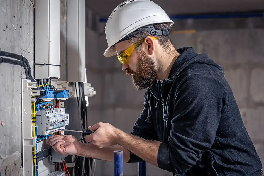 Ruby Electric, Inc.—An electrician works in a switchboard with an electrical connecting cable to stay in accordance with local electrical codes in Springfield, IL.
